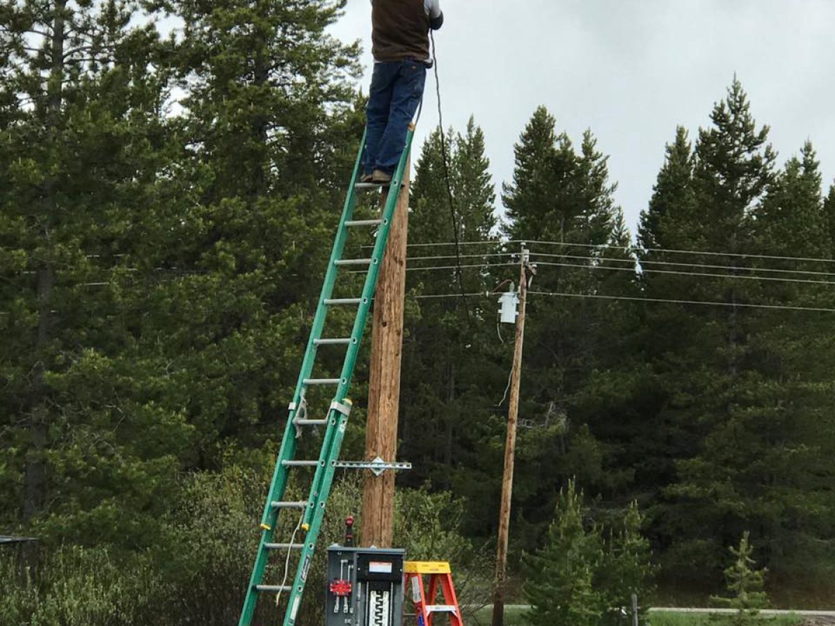 A picture of Platinum Electric team member standing on a ladder to fix the public lighting and breaker box